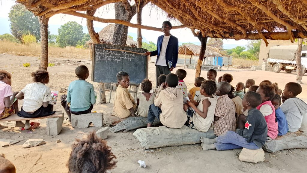 Teacher Leonardo gives a lesson outside at Lusite School before the construction of 4 new classrooms